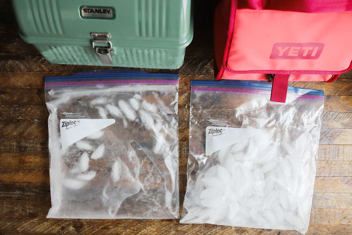 two lunch boxes beside on another and two bags of ice in front of them