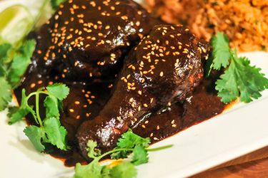 Two chicken drumsticks covered in mole poblano