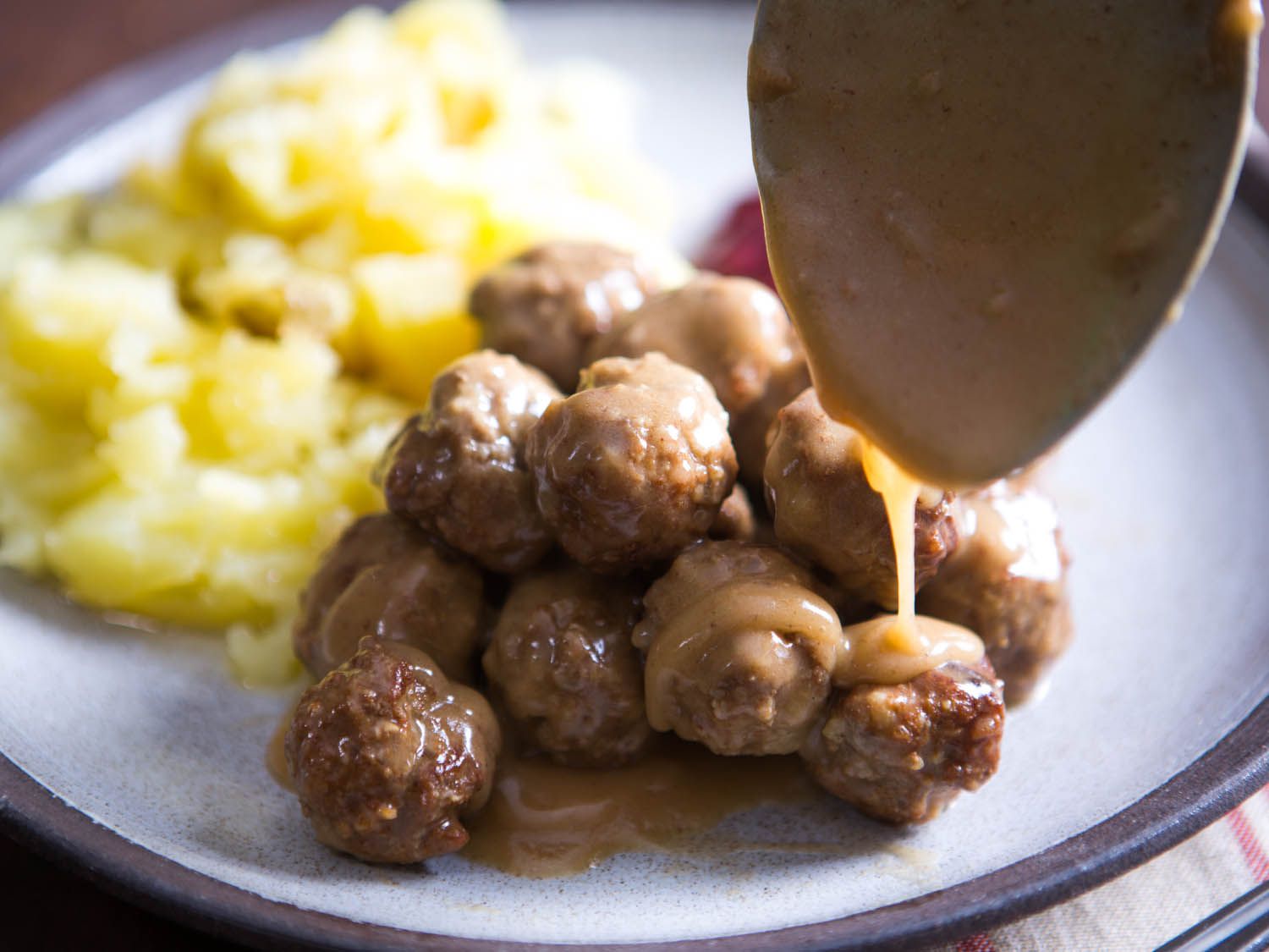 Pouring rich gravy over homemade Swedish meatballs.