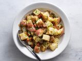 German potato salad in a white ceramic bowl with a spoon.