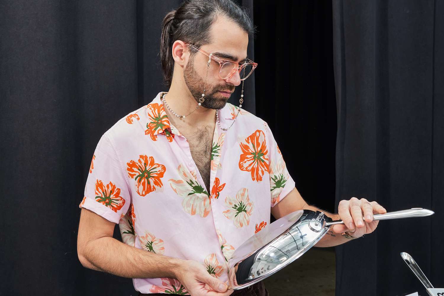 A person inspecting the bottom of a stainless steel skillet