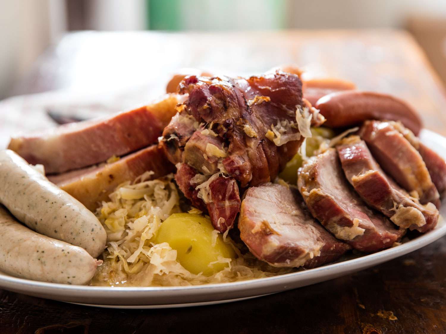 choucroute garnie的特写。德国酸菜和一个土豆占据了画面中各种香肠和新鲜腌猪肉片之间的一小块空隙。gydF4y2Ba