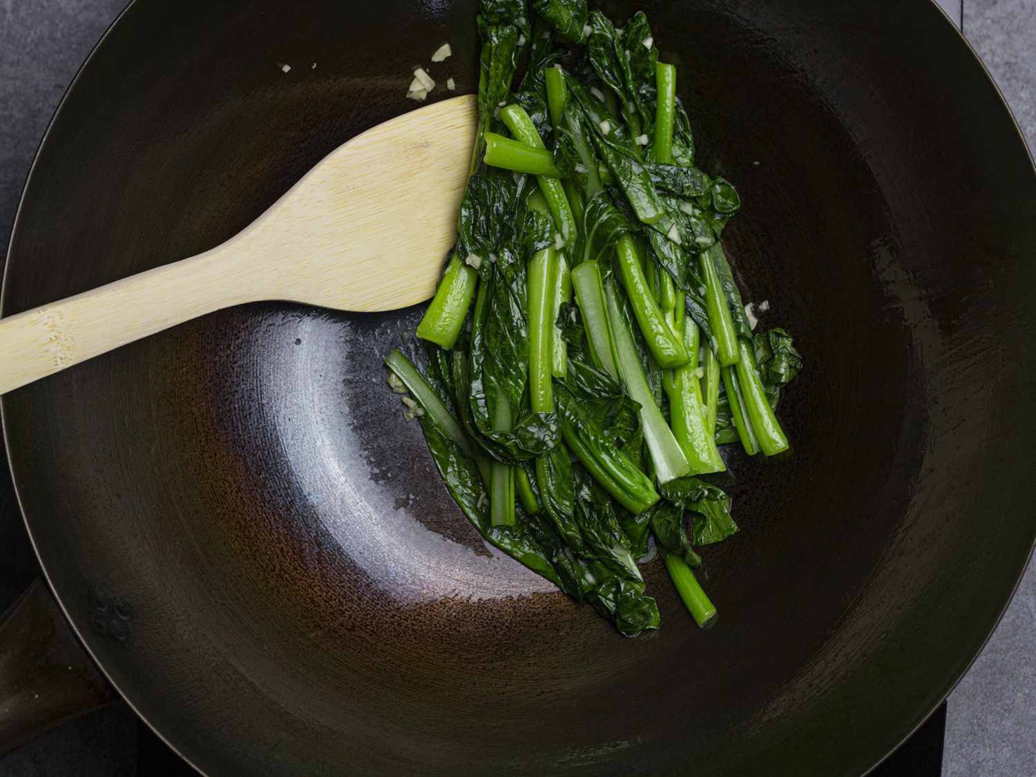 Greens being stir-fried in a wok