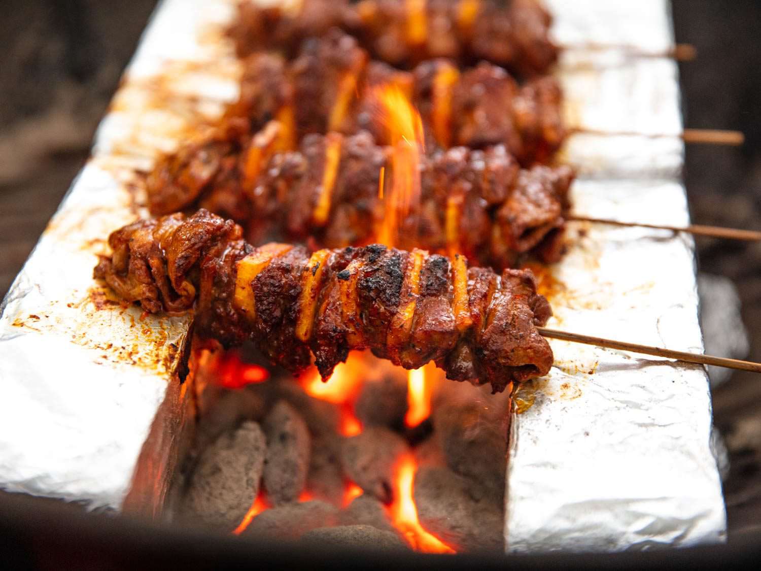 Flames licking up the sides of al pastor skewers.