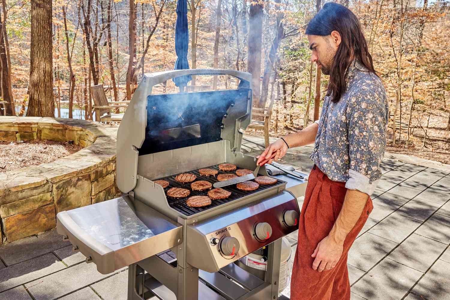 a person flipping burgers on a Weber grill