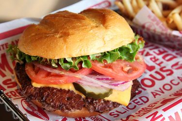 A Smash Burger with a container of french fries behind it