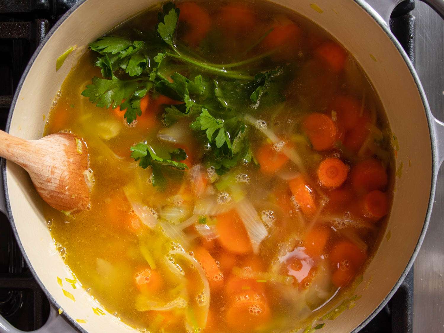 把高汤搅入炒好的胡萝卜和韭菜中做汤。