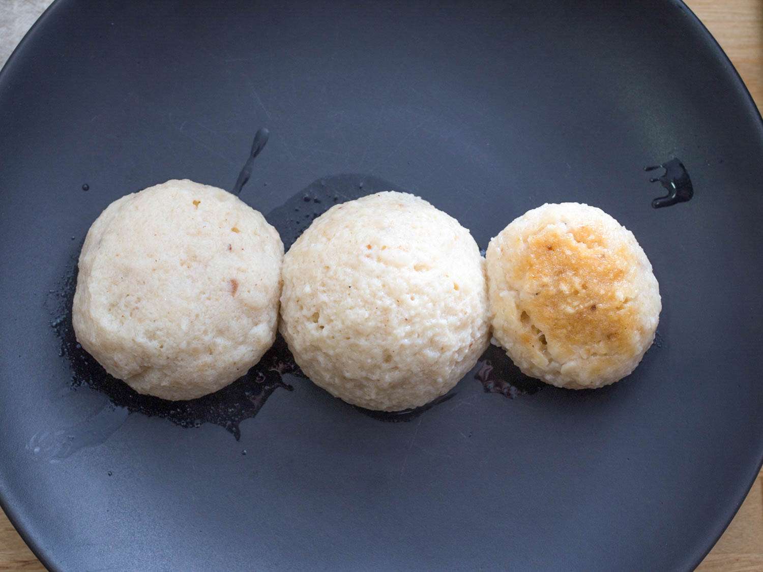 Three matzo balls. The one on the right is significantly smaller and a little discolored.