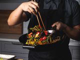 A chef stir-frying colorful vegetables