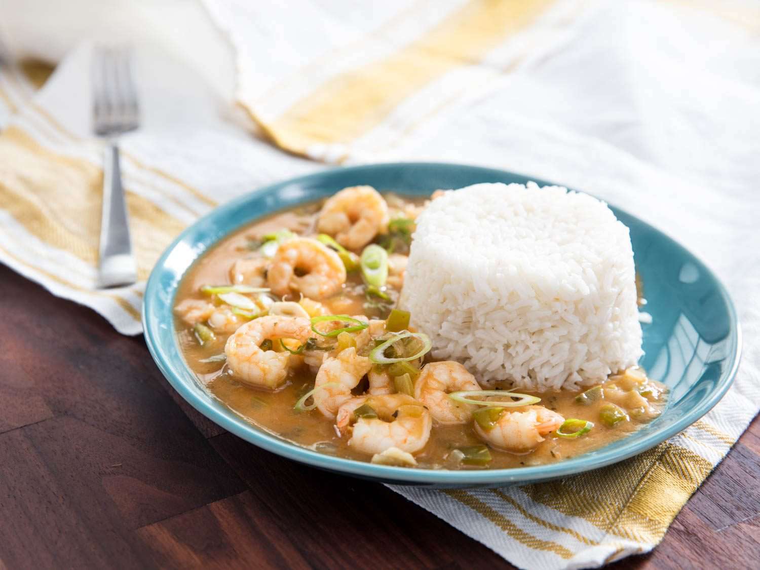 Shrimp étouffée on a blue plate with a mound of rice on top.