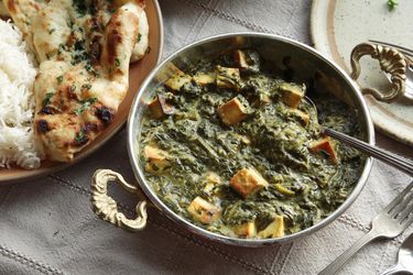 A metal dish filled with vegan saag paneer made with tofu