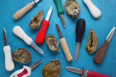 oyster knives on a blue surface with oysters