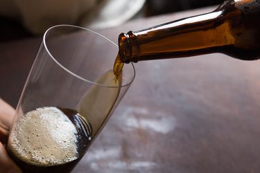 Pouring beer from a bottle into a pint glass.