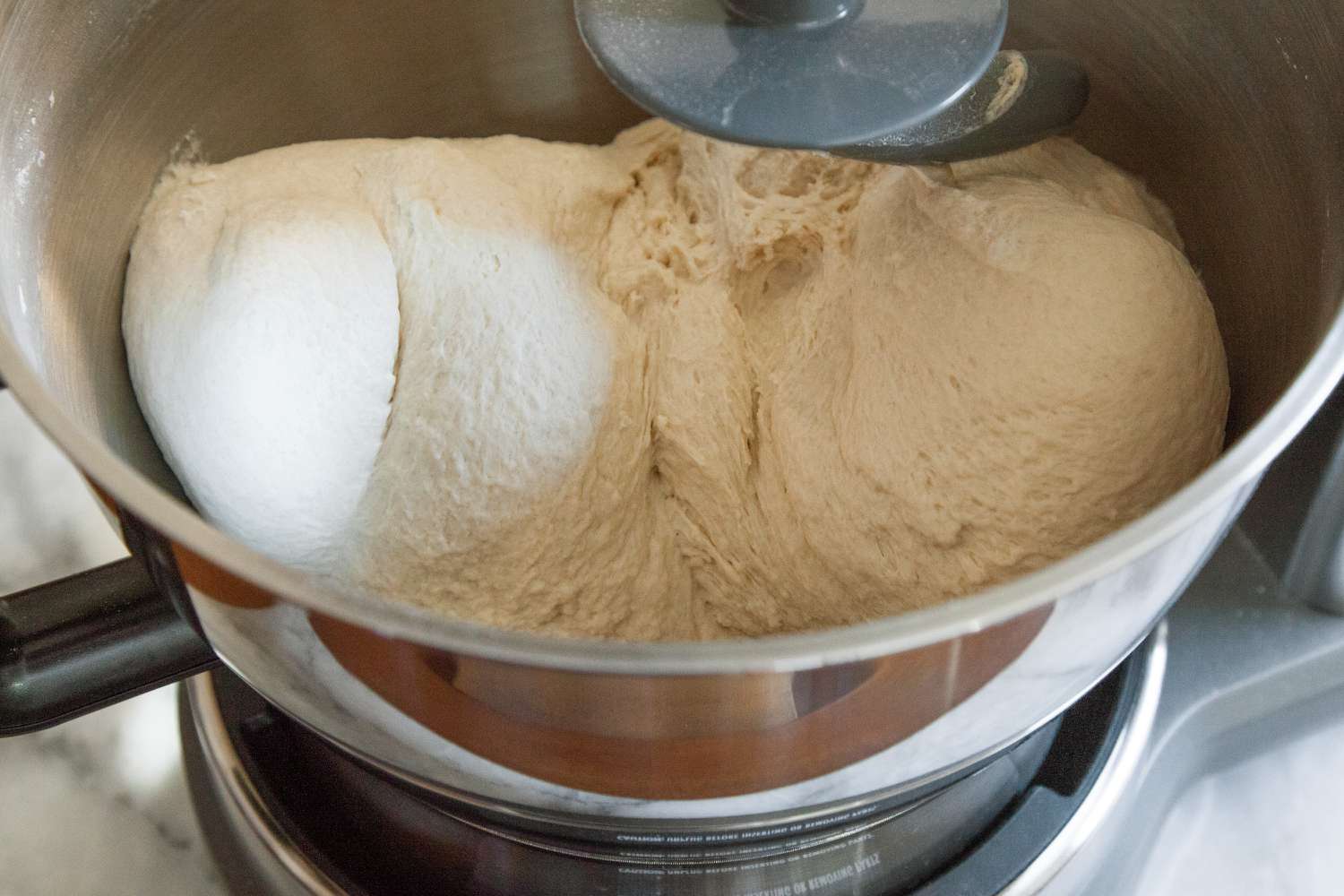 a stand mixer kneading a large batch of pizza dough