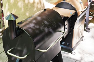 two pellet grills (one black, one bronze) side-by-side