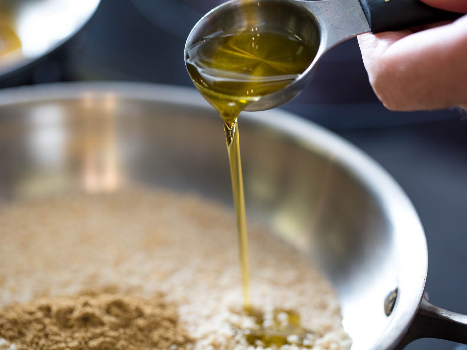 将橄榄油倒入不锈钢平底锅中，平底锅中装有面包屑和茴香籽gydF4y2Ba